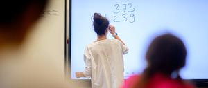 ARCHIV - 17.08.2023, Niedersachsen, Hannover: Eine Lehrerin schreibt eine Mathematikaufgabe auf eine digitale Schultafel im Klassenraum einer 4. Klasse einer Grundschule. (zu dpa: «Südwesten kann nach Pisa-Debakel mit neuem Mathe-Unterricht rechnen») Foto: Julian Stratenschulte/dpa +++ dpa-Bildfunk +++