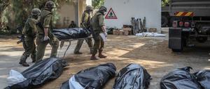 Israelische Streitkräfte bergen die Leichen israelischer Bewohner aus einem zerstörten Haus.