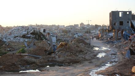 Menschen gehen vorbei an Trümmern und Ruinen auf einer Straße im Flüchtlingslager Al-Maghazi im Zentrum des Gazastreifens. (Bild aufgenommen am 5.03.2024)