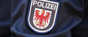 Das Logo der Brandenburger Polizei mit rotem Adler und Schriftzug auf dem Ärmel der Jacke einer Polizeibeamtin (Symbolfoto).