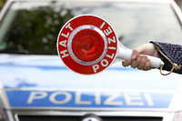 Ein Polizist hält bei einer Sonderkontrolle eine Polizeikelle.