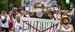 Ein Mann mit Mundschutz hält ein Plakat mit der durchgestrichenen Aufschrift „Putinizm“ (Putinismus) bei einem Protest zur Unterstützung von Sergej Furgal, dem Gouverneur der Region Chabarowsk, in der Hand.