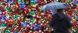 Keine weißen Weihnachten: Ein Mann mit Regenschirm steht auf dem Weihnachtsmarkt am Potsdamer Platz in Berlin (Archivbild).