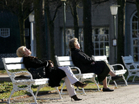 Ein Rentnerpaar sitzt auf einer Bank und sonnt sich (Symbolbild).