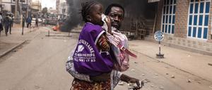 A man runs with his daughter as she covers her nose from teargas in Dakar on March 16, 2023. - Security forces were deployed in the Senegalese capital Dakar on March 16, 2023 ahead of a politically-charged trial of an opposition leader. Ousmane Sonko is being tried for allegedly defaming a minister, a case that could determine whether he will be eligible to run in presidential elections next February. (Photo by JOHN WESSELS / AFP)