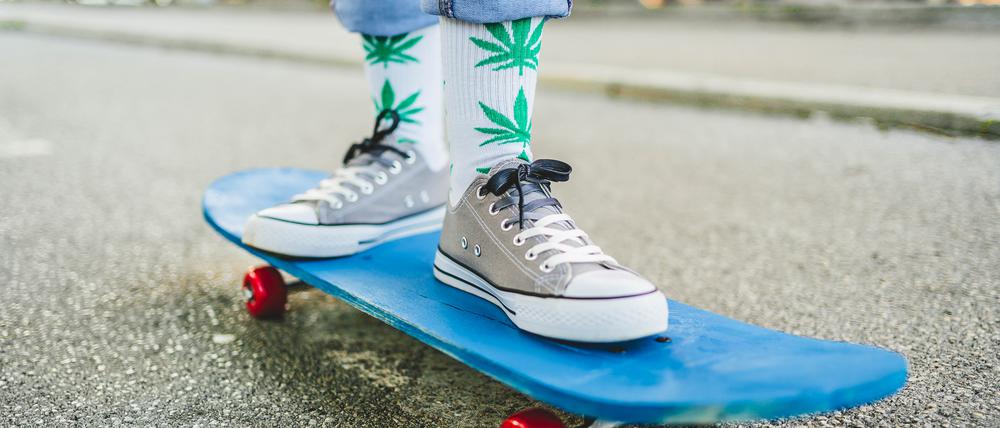 Junge Frau mit Marihuana-Socken auf einem Skateboard.