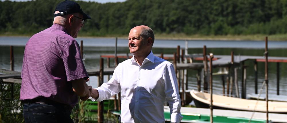 Händeschütteln – in der Hoffnung auf Hilfe: Bundeskanzler Olaf Scholz macht sich mit Eckhard Syring vom Angelverein Wildenbruch ein Bild vom See.