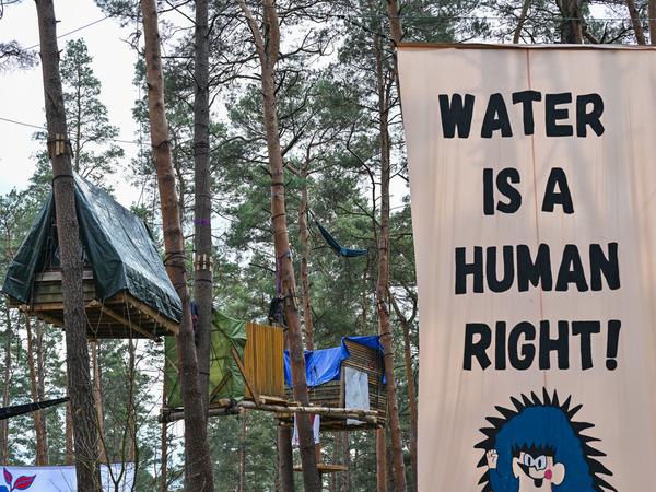 Ein Transparent mit der Aufschrift «Water is a human right!» hängt zwischen den Bäumen im Camp von Aktivisten der Initiative «Tesla stoppen» nahe der Tesla-Gigafactory Berlin-Brandenburg.