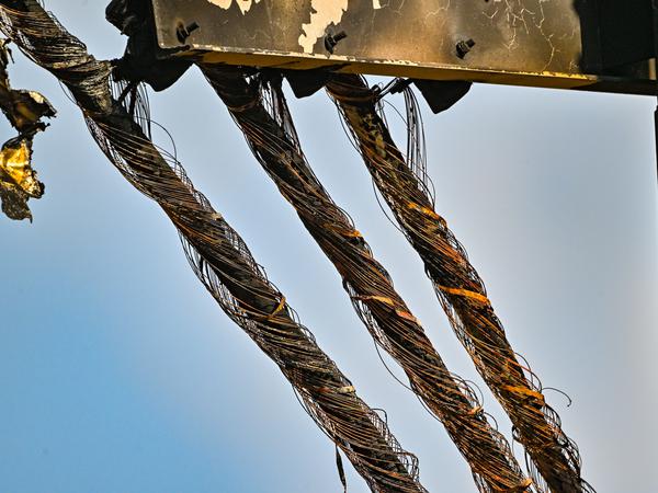 Verbrannte Kabel hängen an einem Strommast auf einem Feld nahe der Tesla-Autofabrik.