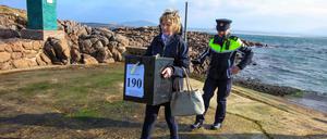 Garda Felicia Coll trägt eine Wahlurne auf die Insel Gola in Irland. 