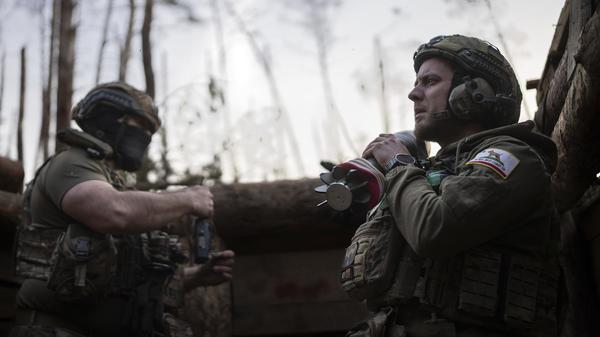 Ein ukrainischer Soldat der Asow-Brigade, bekannt unter dem Rufnamen Chaos, rechts, trägt eine Mörsergranate, während er auf einen Feuerbefehl wartet. 