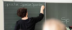 Eine Lehrerin schreibt in einer Grundschule Wörter an eine Tafel. 