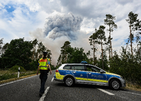 Ein Polizei Auto sperrt die Straße in einem Waldbrandgebiet in der Gohrischheide ab. In der Gohrischheide an der Landesgrenze zu Brandenburg ist ein munitionsbelastetes Waldstück in Brand geraten.