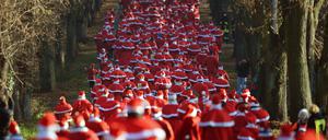 Hunderte Läufer in Weihnachtsmannkostümen laufen am 07.12.2014 in Michendorf (Brandenburg) während des traditionellen Weihnachtsmannlaufes durch eine Allee. Das Laufevent findet zum sechsten Mal statt. Foto: Ralf Hirschberger/dpa +++(c) dpa - Bildfunk+++