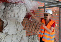 Stephanie Hochberg von der Stiftung Garnisonkirche Potsdam zeigt einen aus Sandstein gehauenen Prunkhelm am Sockelbau der Garnisonkirche.
