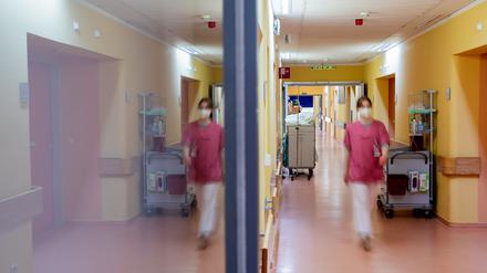 Eine Pflegehelferin geht im Gang der Viszeralchirurgie-Station des Krankenhauses Havelhöhe, wobei sie sich in einer Glastür spiegelt. 