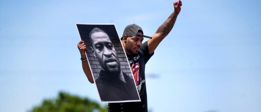 Ein Demonstrant hält ein Foto des getöteten George Floyd hoch.