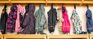 Jacken von Kindern hängen an der Garderobe einer Kita.