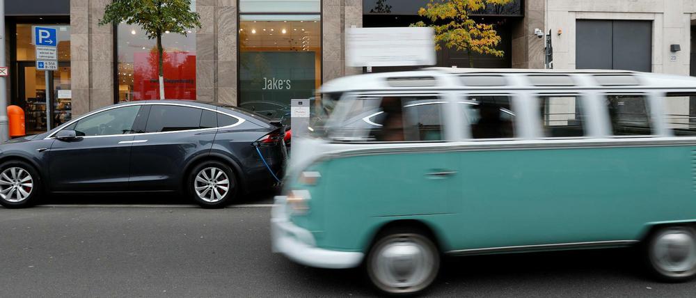Ein Oldtimer von VW fährt an einem Tesla in Berlin vorbei 