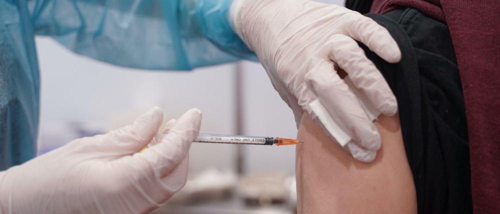 Ein junger Mann wird mit einer Booster-Dosis eines Corona-Impfstoffs geimpft.