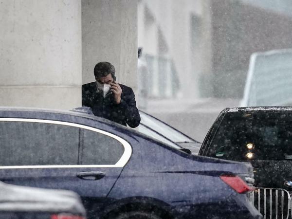 Markus Söder steht am Dienstagnachmittag bei dichtem Schneefall telefonierend vor dem Bundeskanzleramt.