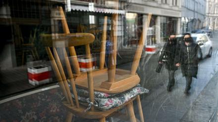Hochgestellte Stühle sind durch die Scheibe eines Cafés in der Kneipenmeile von Halle/Saale. 