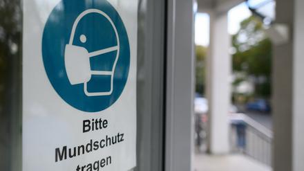 Ein Schild ´Bitte Mundschutz tragen` ist am Eingang eines Krankenhauses angebracht. 