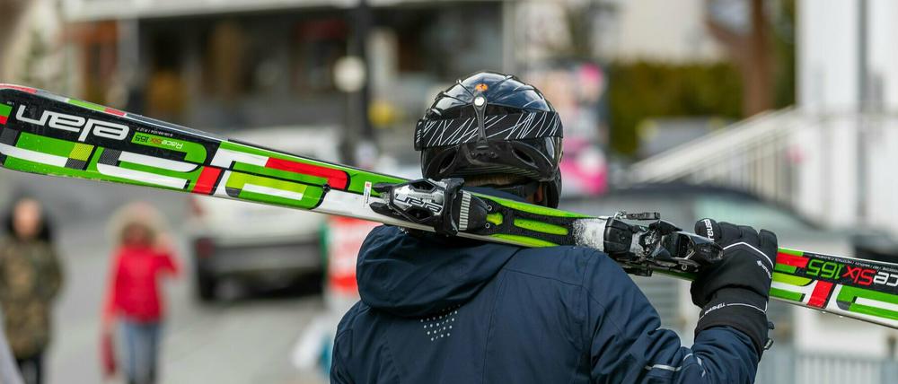 Ein Skifahrer geht mit geschulterten Skiern auf einer Straße. Tirol hat die Skisaison vorzeitig beendet. Die Region Paznauntal mit dem Touristenort Ischgl steht in Österreich neben weiteren Orten wegen einer erhöhten Zahl von Coronavirus-Fällen unter Quarantäne. 