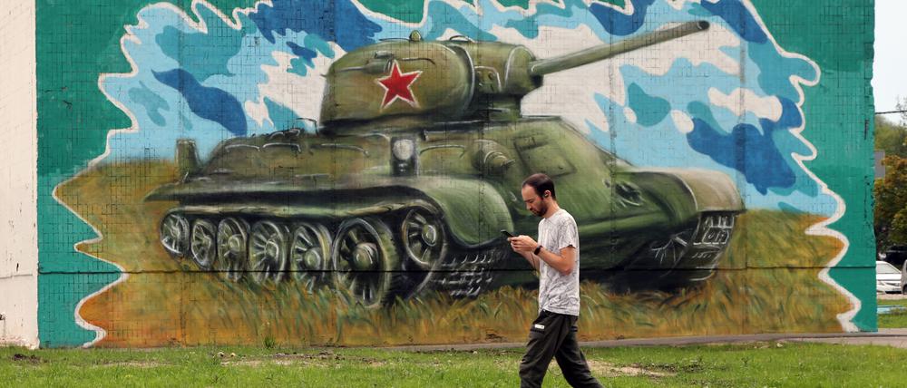 Ist das schon Krieg oder noch Spaziergang? Ein Mann läuft in Moskau an einem Panzergraffiti vorbei.
