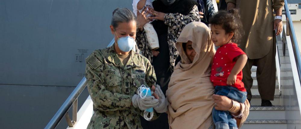 Eine amerikanische Soldatin hilft einer Afghanin auf einem US-Luftwaffenstützpunkt in Italien beim Aussteigen aus einer Evakuierungsmaschine.