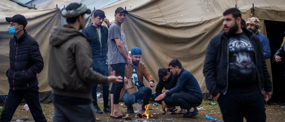 Migranten bereiten in einem neu errichteten Flüchtlingslager auf dem Truppenübungsplatz Rudninkai Essen zu. 