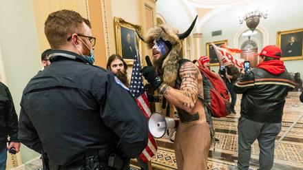 Ein Unterstützer von US-Präsident Trump steht auf dem Gang vor der Senatskammer im US-Kapitol und diskutiert mit einem Polizisten des Kapitols.