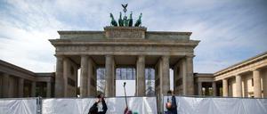 Besucher fotografieren von den Feiern zum Einheitstag über einen Zaun vor dem Brandenburger Tor. 