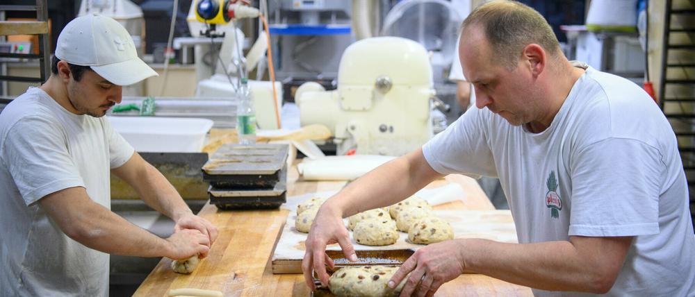 Bäcker Guido Marzillier (r.), stellvertretender Backstubenleiter in der Bäckerei und Konditorei Plentz, und Bäcker Benjamin Fischer formen mit den Händen den Teig für Marzipanstollen.