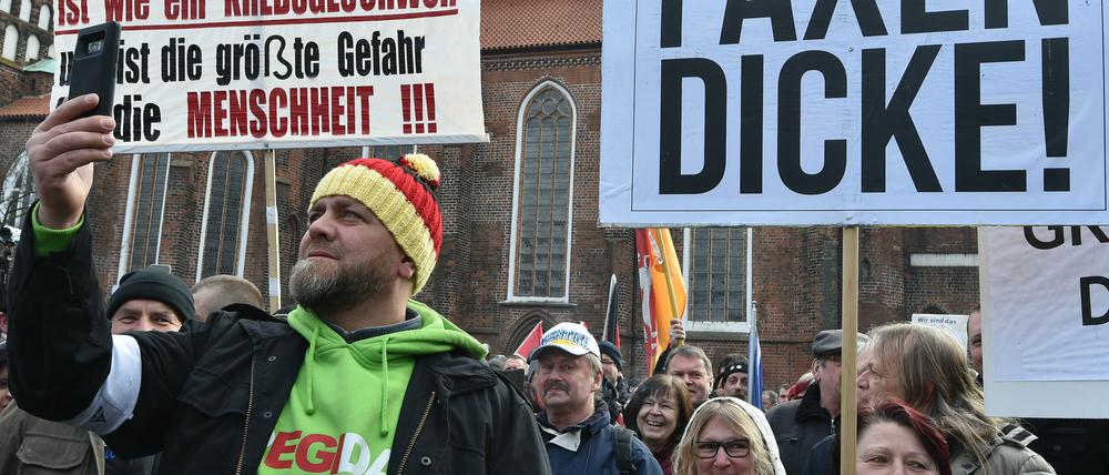 Brandenburg, Cottbus: Ein Demonstrant filmt mit dem Handy die Plakate auf dem Oberkirchplatz. Der Verein Zukunft Heimat e.V. hatte zu der Demonstration aufgerufen.