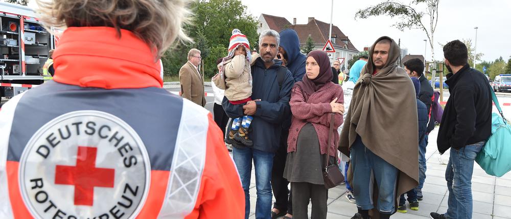 DRK-Helfer weisen Flüchtlingen nach ihrer Ankunft mit einem Zug aus München in Eisenhüttenstadt den Weg zur medizinischen Erstaufnahme. Neonazis wollen in Eisenhüttenstadt demonstrieren.