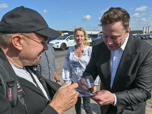Elon Musk gibt Tesla-Fan Hans-Jürgen Michelsen ein Autogramm.