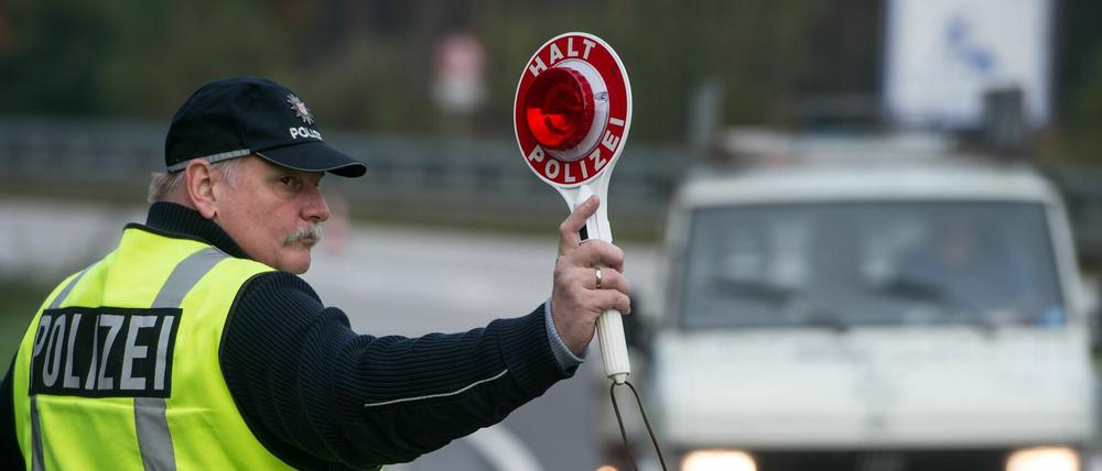 Ein Polizeibeamter winkt mit einer Kelle zu einer Verkehrskontrolle.