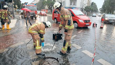 Einsatz am Gullydeckel. Feuerwehrmänner in der überfluteten West-City.