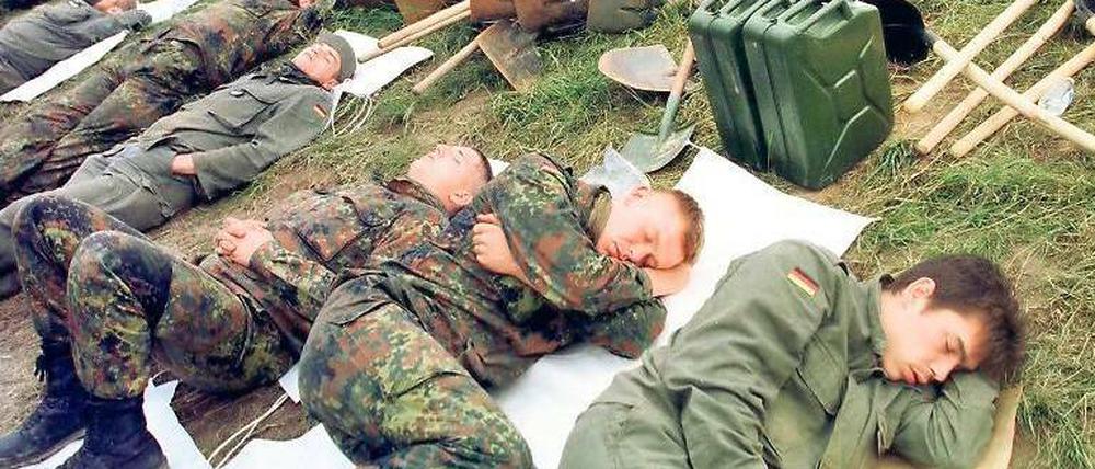 Schlafmangel. Nach 18 Stunden Dauereinsatz ruhen sich erschöpfte Bundeswehrsoldaten im Juli 1997 am Deich von Hohenwutzen aus. Insgesamt 30 000 Soldaten waren während der Hochwasserkatastrophe im Odergebiet im Einsatz.