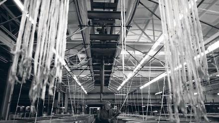 Grisuten für Chemiefasern. In der Märkischen Faser AG in Premnitz kontrolliert ein Mitarbeiter Polyesterfasern, die zu einem gemeinsamen Strang für die Textilindustrie zusammengeführt werden.
