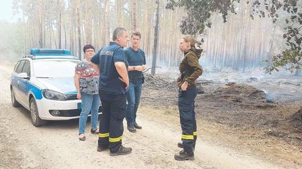 Spurensuche. Kommissar Frank Tiews (Mitte) lässt sich von den Feuerwehrleuten Olaf Fetz und Ulrike Fischer zeigen, wo der Brand hinter Frohnsdorf ausbrach.