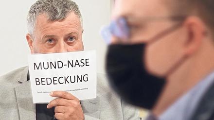 Im Landtag, auch im Plenarsaal, gilt inzwischen Maskenpflicht. Der AfD-Abgeordnete Michael Hanko hält sich während einer Landtagssitzung ein Schild vors Gesicht. Die AfD zweifelt den Nutzen von Masken an.