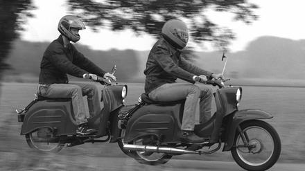 Zwei junge Männer fahren mit ihren "Schwalbe"-Rollern über einen Feldweg.