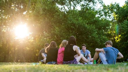 Jugendliche sitzen in den letzten Sonnenstrahlen am Tiergarten. 