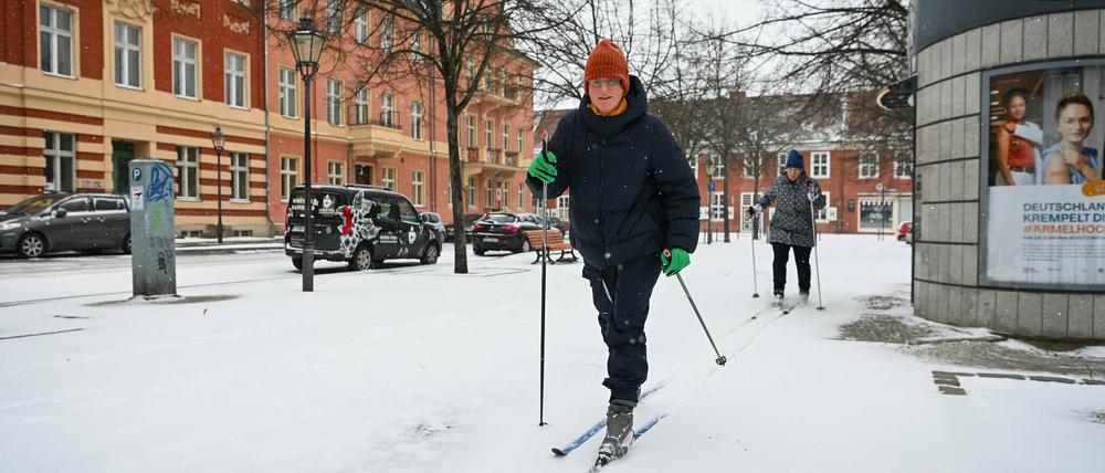 Zwei Potsdamerinnen fahren auf Langlauf-Ski über den schneebedeckten Fußweg am Bassinplatz. 