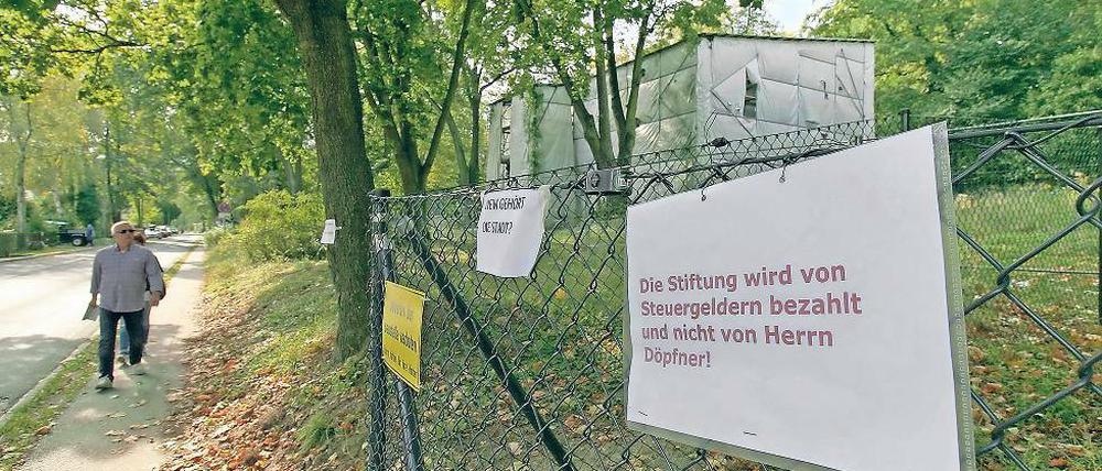 Streit unter Nachbarn. Mit Schildern wird gegen den Bauzaun protestiert, den Mathias Döpfner im Auftrag der Schlösserstiftung um das Grundstück der Gartenanlage der Villa Henckel und der Villa Schlieffen errichten ließ.