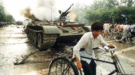 Menschen fliehen vor 30 Jahren vor einem in Brand gesetzten Panzer westlich des Tien An Men-Platzes in Peking.