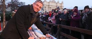 Potsdams Oberbürgermeister Mike Schubert (SPD) schneidet auf dem Weihnachtsmarkt den Riesenstollen an.