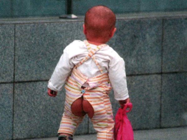 Aus dem Leben. Ein Junge in Shanghai tobt mit besonderer Hosenmode über die Straße.